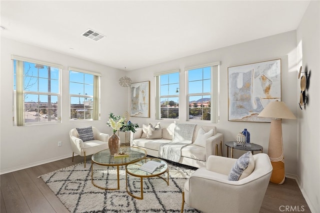 living area featuring visible vents, plenty of natural light, baseboards, and wood finished floors