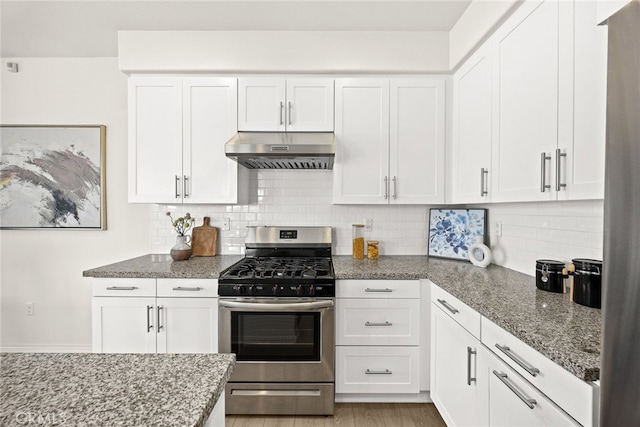 kitchen with under cabinet range hood, stainless steel gas range oven, stone countertops, and white cabinets