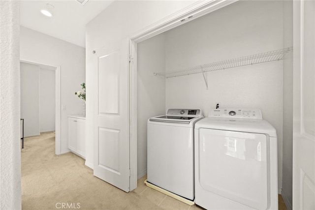 clothes washing area featuring light colored carpet, laundry area, and washing machine and clothes dryer