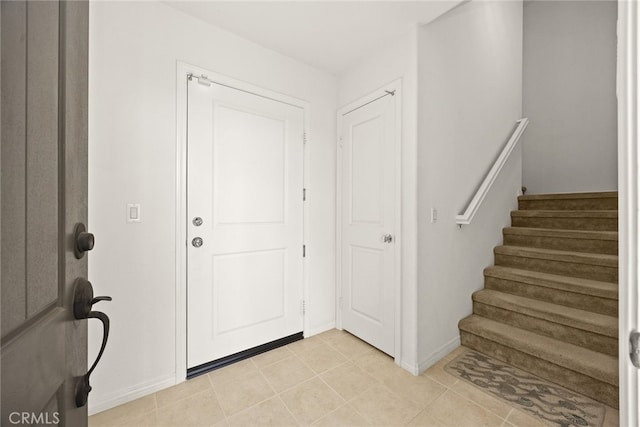 foyer with stairway, light tile patterned flooring, and baseboards