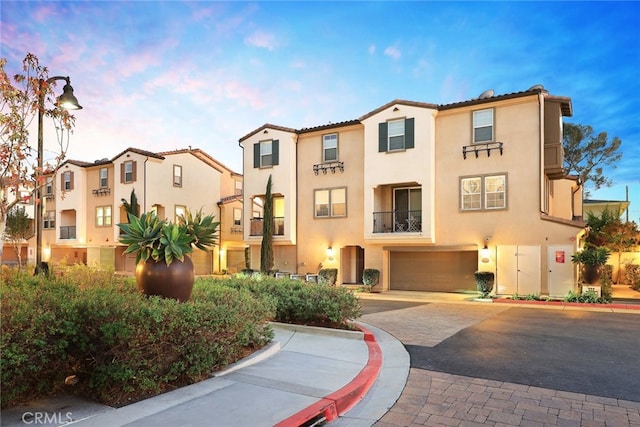 mediterranean / spanish-style house with stucco siding, an attached garage, driveway, and a tile roof