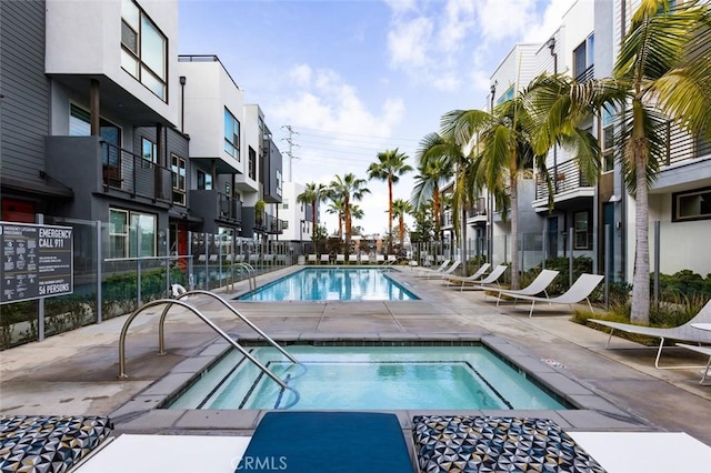 pool featuring a residential view, a patio, a community hot tub, and fence