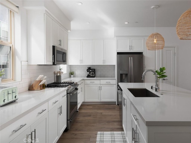 kitchen featuring dark wood-style floors, a sink, stainless steel appliances, white cabinets, and tasteful backsplash