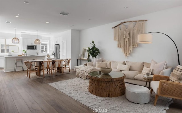 living room with recessed lighting, wood finished floors, and visible vents