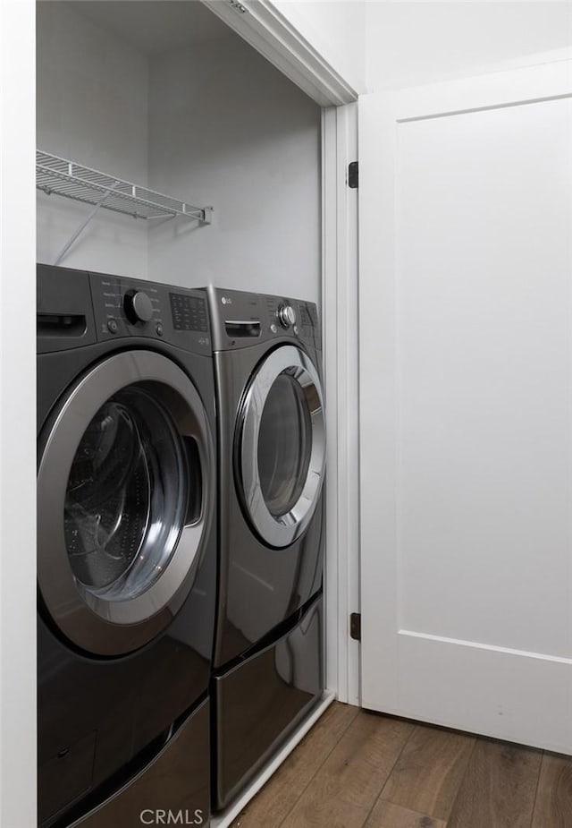 laundry area featuring washer and clothes dryer, laundry area, and wood finished floors