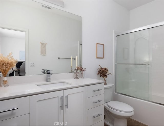 full bath featuring visible vents, toilet, vanity, and bath / shower combo with glass door