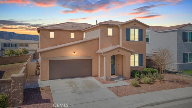 mediterranean / spanish-style home featuring fence, an attached garage, stucco siding, concrete driveway, and a tile roof