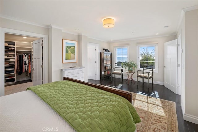 bedroom with ornamental molding, a walk in closet, baseboards, and dark wood-style flooring