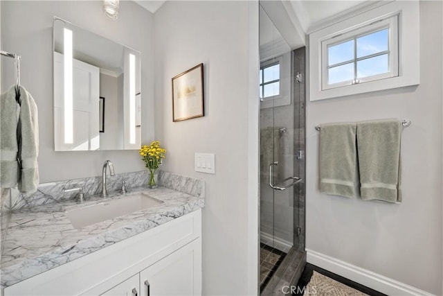 bathroom with a shower stall, vanity, and baseboards