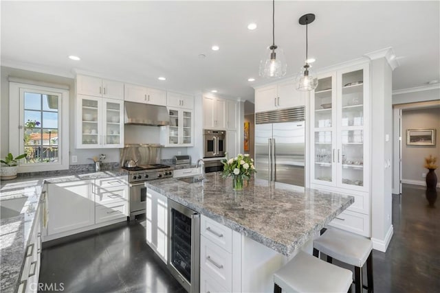 kitchen with beverage cooler, under cabinet range hood, premium appliances, white cabinets, and crown molding