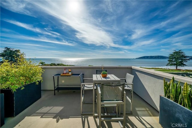 view of patio with a balcony, outdoor dining area, and a water view