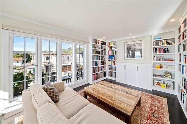 living area with built in shelves, wood finished floors, recessed lighting, and ornamental molding