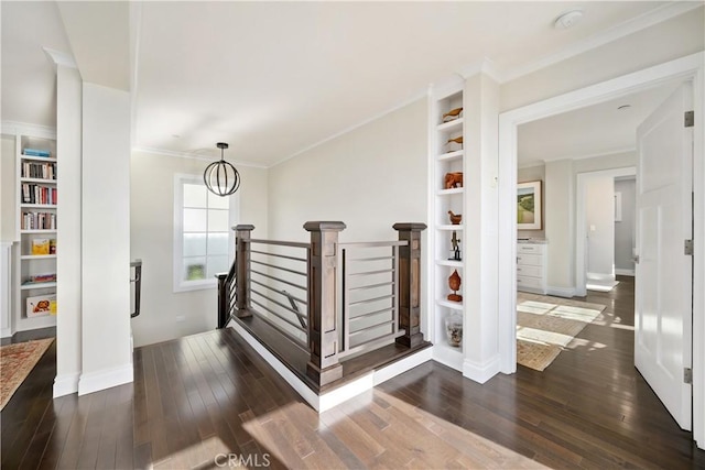 hall with dark wood-type flooring, an upstairs landing, a chandelier, and ornamental molding