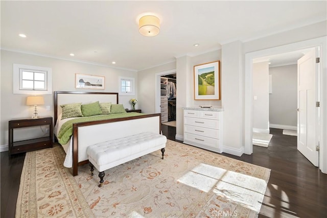 bedroom featuring baseboards, dark wood finished floors, recessed lighting, a spacious closet, and crown molding