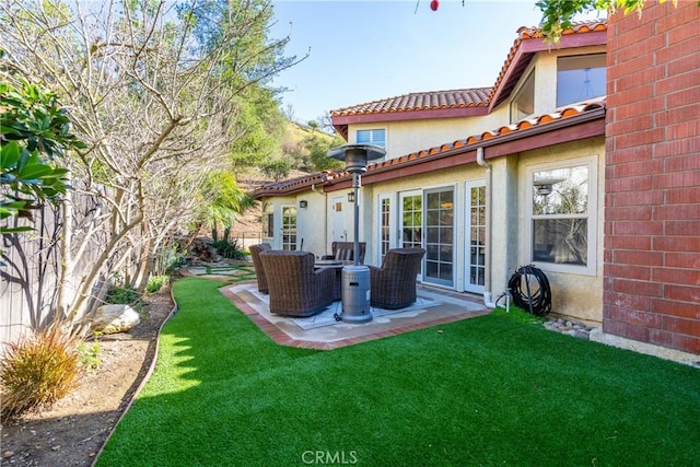 rear view of house with a patio, a lawn, brick siding, and a tiled roof