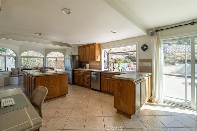 kitchen featuring a center island, recessed lighting, brown cabinets, a peninsula, and stainless steel appliances