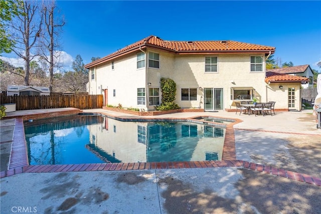 rear view of property with a fenced in pool, fence, a tiled roof, stucco siding, and a patio area