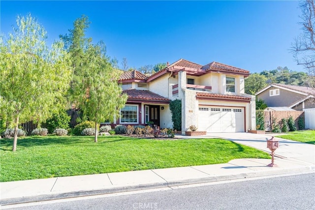 mediterranean / spanish home featuring stucco siding, driveway, a front yard, a garage, and a tiled roof