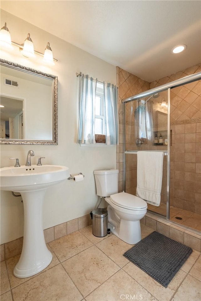 bathroom featuring visible vents, a shower stall, baseboards, toilet, and tile patterned floors
