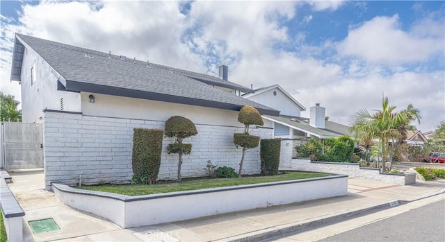 view of side of home with a shingled roof and fence