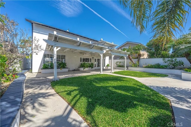 rear view of property featuring fence, stucco siding, a yard, a pergola, and a patio