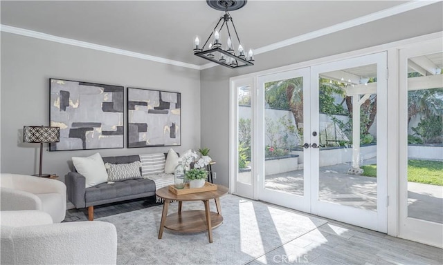 living room with crown molding, wood finished floors, french doors, and a chandelier