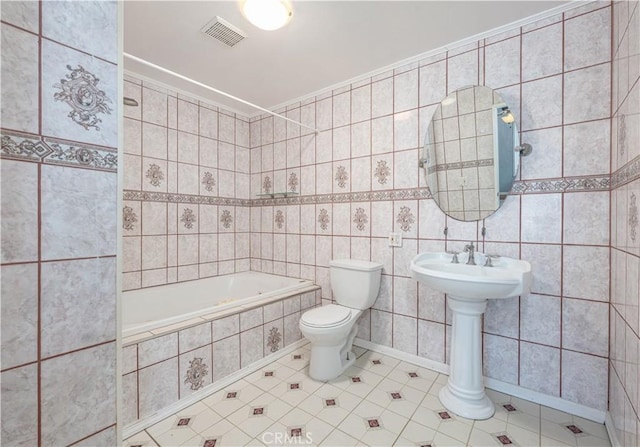 bathroom with visible vents, tiled tub, tile patterned flooring, tile walls, and toilet