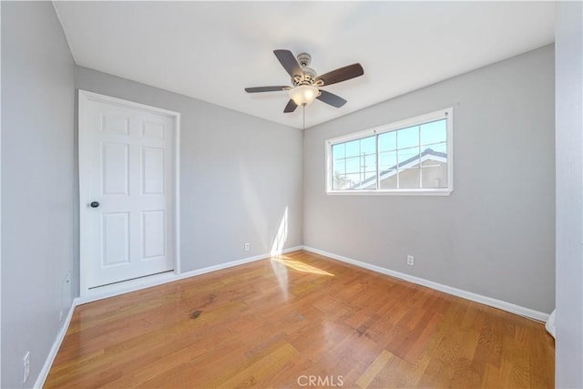 spare room featuring ceiling fan, baseboards, and wood finished floors