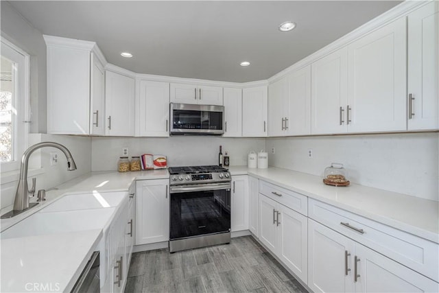 kitchen with light wood-style flooring, appliances with stainless steel finishes, and white cabinetry