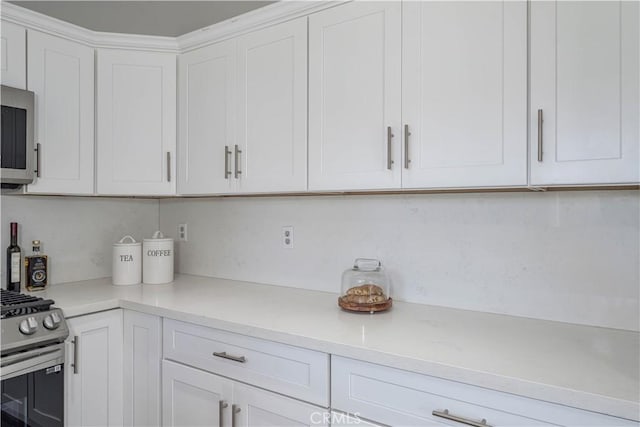 kitchen featuring stainless steel appliances, white cabinetry, and light countertops