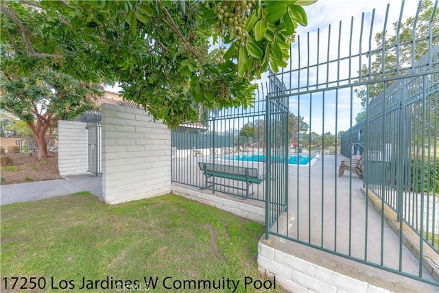 view of gate featuring a yard, a community pool, and fence