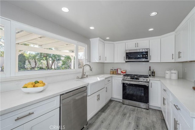 kitchen featuring a sink, stainless steel appliances, light countertops, and white cabinetry