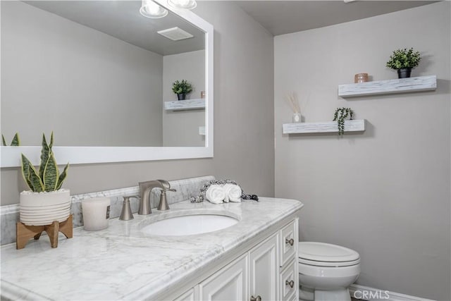 bathroom featuring visible vents, toilet, and vanity