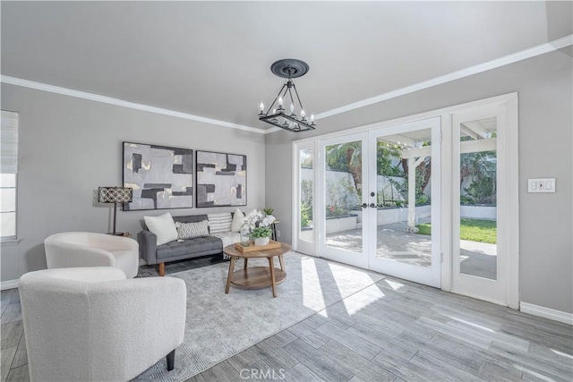 living room with crown molding, baseboards, french doors, wood finished floors, and a notable chandelier