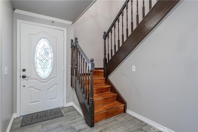 foyer with stairs, ornamental molding, baseboards, and wood finish floors