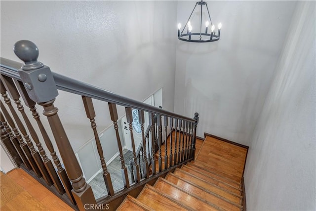 staircase featuring an inviting chandelier and wood finished floors