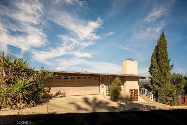 ranch-style house with stucco siding, a garage, concrete driveway, and a chimney