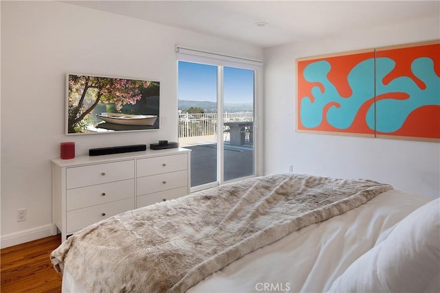 bedroom featuring access to exterior, wood finished floors, and baseboards