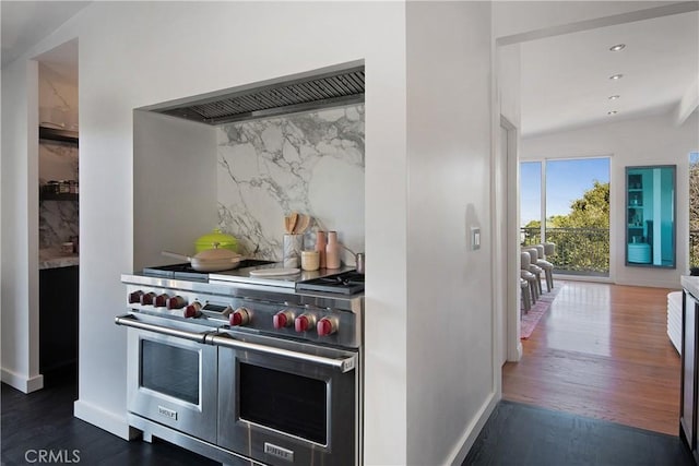 kitchen with custom range hood, wood finished floors, range with two ovens, decorative backsplash, and baseboards