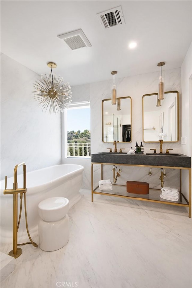 full bathroom featuring a freestanding tub, visible vents, marble finish floor, and a sink