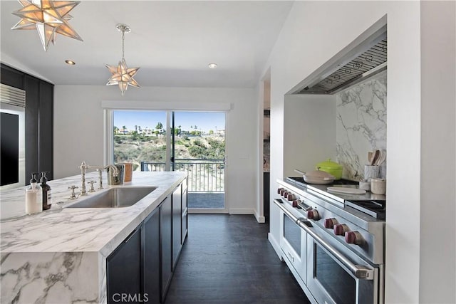 kitchen with tasteful backsplash, a sink, double oven range, wall chimney exhaust hood, and dark cabinets