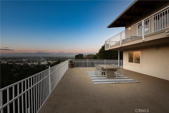 patio terrace at dusk featuring a balcony and outdoor dining area