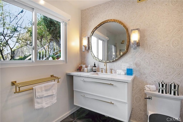 bathroom featuring toilet, vanity, and baseboards