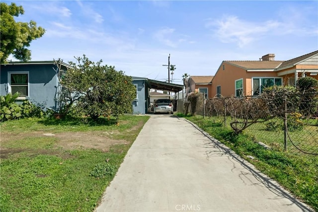 surrounding community with an attached carport, a lawn, driveway, and fence