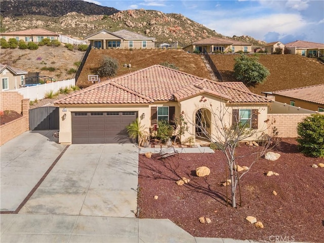 mediterranean / spanish house with a tiled roof, concrete driveway, stucco siding, a garage, and a mountain view