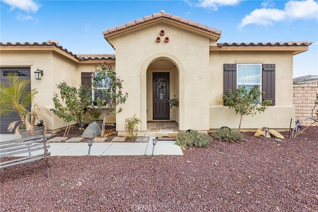 view of front of home with stucco siding, a tiled roof, and an attached garage