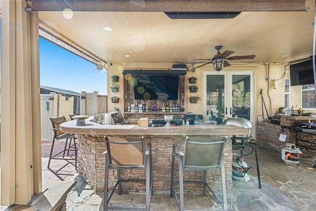 view of patio featuring grilling area, fence, french doors, outdoor wet bar, and a ceiling fan