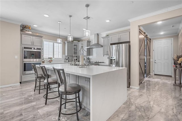 kitchen with visible vents, a barn door, gray cabinets, appliances with stainless steel finishes, and wall chimney exhaust hood