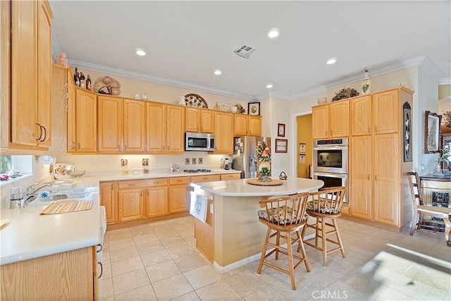 kitchen with visible vents, a kitchen island, light brown cabinetry, appliances with stainless steel finishes, and a sink