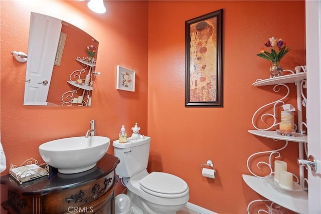 half bathroom featuring vanity, toilet, and baseboards